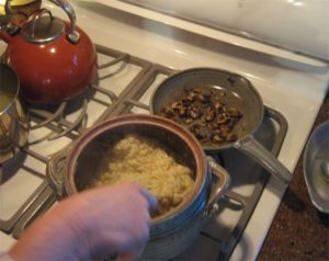 photo of someone cooking on a stove with a pot and skillet