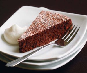 photo of a triangle slice of chocolate mousse torte on a plate with powdered sugar on top