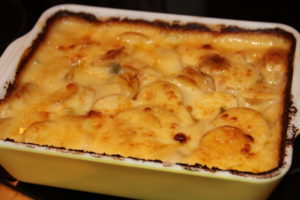 photo of a bubbling potato casserole in a casserole dosh with burnt edges