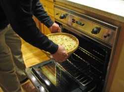 photo of a man putting a cassole with a cassoulet inside into the oven