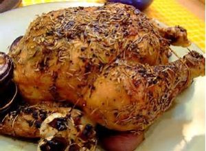 photo of a whole chicken roasted with rosemary on top