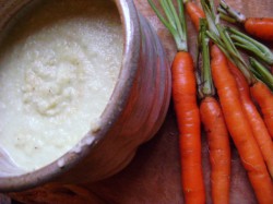 a photo of dip in a bowl with fresh carrots next to it