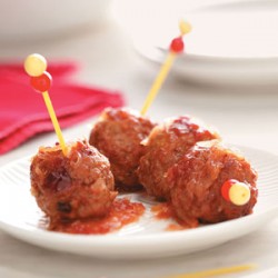 photo of 4 meatballs with yellow skewers through them on a plate