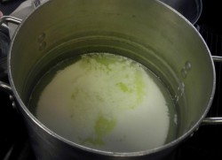 photo of the proccess of making homemade cheese - white cream at bottom of metal pot