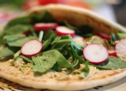 photo of falafal on pita bread with spinach and radishes