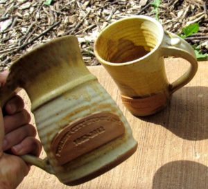 photo of two yellow ceramic mugs with forest city stockade imprinted on them