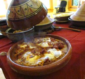 photo of a tagine dish on the table with meat and eggs in it