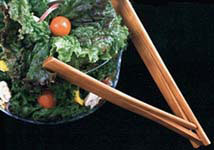 photo of wooden tongs next to a salad
