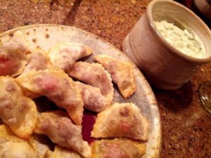 photo of a plate of empanadas and a cup of cilantro sour cream