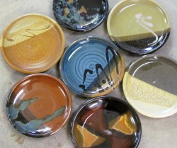 photo of 7 ceramic plates each with a different glaze. plates arranged in a flower shape
