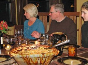 photo of people sitting at a dining table with a cassole in the middle of the table