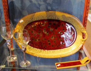 photo of a red and yellow ceramic platter next to two crystal wine glasses