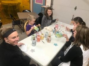 photo of 5 ladies sitting around a table painting ornaments