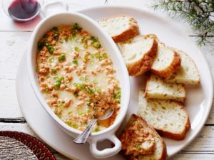 photo of a shrimp dip with scallions on top and bread pieces next to it