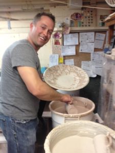 photo of a man holding a pot while glazing it 