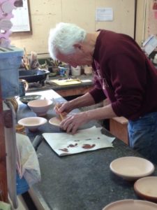 photo of a older man painting pottery