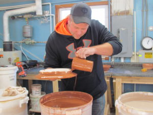 photo of joe nagel pouring glaze on a piece of pottery