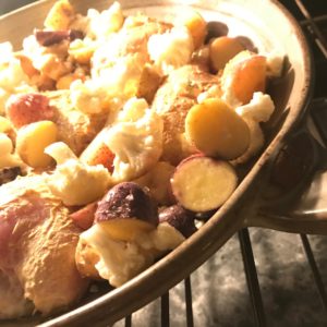 close up photo of chicken and vegetables in a skillet in the oven