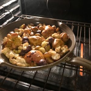 photo of chicken and veggies in a skillet in the oven