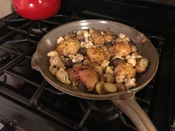 photo of a clay skillet with veggies and chicken on the stovetop