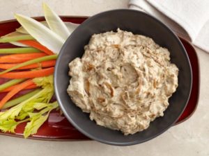 photo of a light brown creamy onion dip in a bowl with a side of celery and carrots