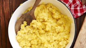 photo of a sweet corn tomalito in a bowl with a wooden spoon