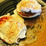 Poached eggs on english muffin topped with swiss cheese pepper sauce and paprika