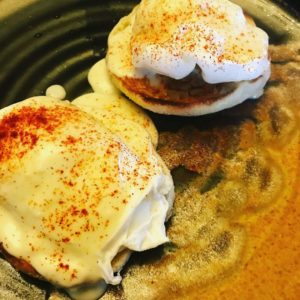 Poached eggs on english muffin topped with swiss cheese pepper sauce and paprika