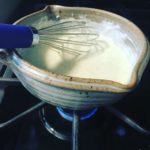 Cheese sauce in saucepan with metal whisk