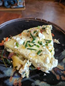 A slice of a late summer frittata on a clay coyote plate