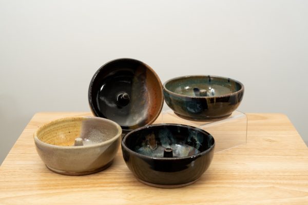 the photograph shows a set of 4 mix-n-match microwave omelette cookers on a small light colored wooden table. starting from the left the glazes on the omelette makers are: mint berry, mocha swirl (to the upper right of the mint berry) midnight garden (to the lower right of the mint berry) and finally a zappa glaze. the mocha swirl omelette cooker is on a plastic stand allowing it to be in a vertical position to show off the glaze pattern. the zappa omelette cooker is on a clear plastic riser stand. the background is a white wall.