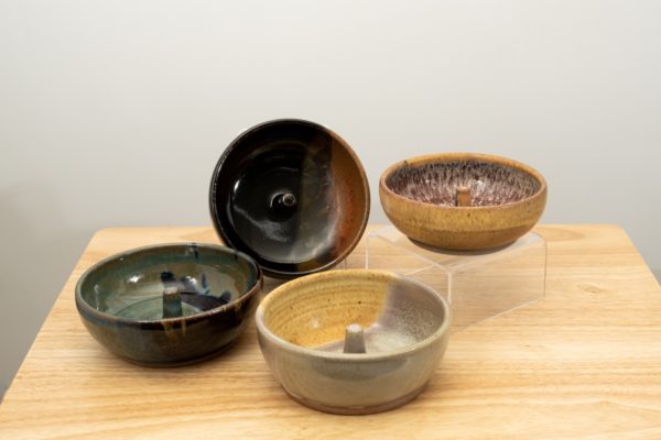 the photograph shows a set of 4 mix-n-match microwave omelette cookers on a small light colored wooden table. starting from the left the glazes on the omelette makers are: zappa, mocha swirl (to the upper right of the zappa) mint berry glaze (to the lower right of the zappa) and finally tequila sunrise glaze. the mocha swirl omelette cooker is on a plastic stand allowing it to be in a vertical position to show off the glaze pattern. the tequila sunrise omelette cooker is on a clear plastic riser stand. the background is a white wall.