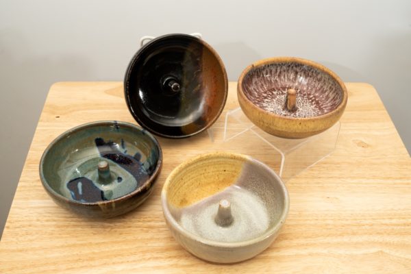 the photograph shows a set of 4 mix-n-match microwave omelette cookers on a small light colored wooden table. starting from the left the glazes on the omelette makers are: zappa, mocha swirl (to the upper right of the zappa) mint berry glaze (to the lower right of the zappa) and finally tequila sunrise glaze. the mocha swirl omelette cooker is on a plastic stand allowing it to be in a vertical position to show off the glaze pattern. the tequila sunrise omelette cooker is on a clear plastic riser stand. the background is a white wall.